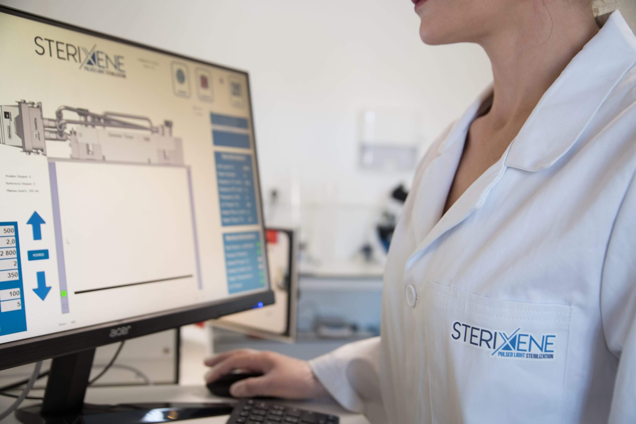 Expertise in UV light system design and microbiological testing at Hoenle’s Class II lab Laboratory workstation with a computer displaying a UV pulsed light system, microbiology testing data on screen and a lab technician using the mouse.